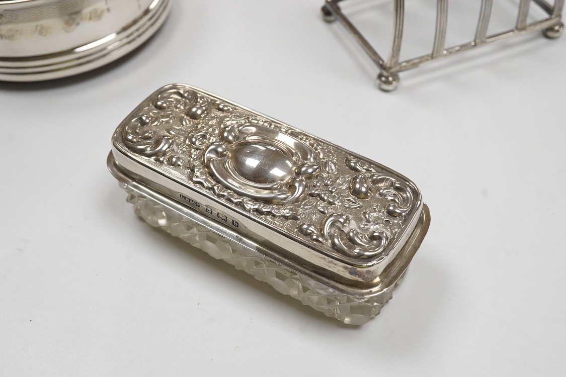 A George III engraved silver helmet shaped cream jug, Henry Chawner, London 1788(repair), height 15.3cm, together with two George V silver toast racks, a silver mounted glass toilet jar and a modern silver mounted bottle